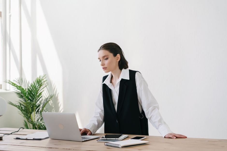 A professional woman in an office setting focused on her laptop, featuring a clean and modern design.