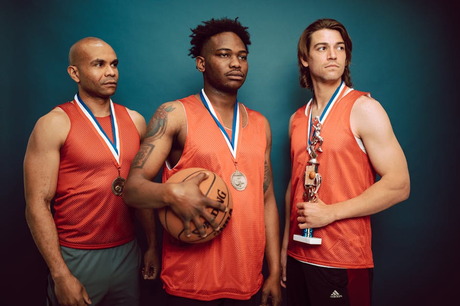 Three basketball players celebrating with medals and a trophy in victory pose.