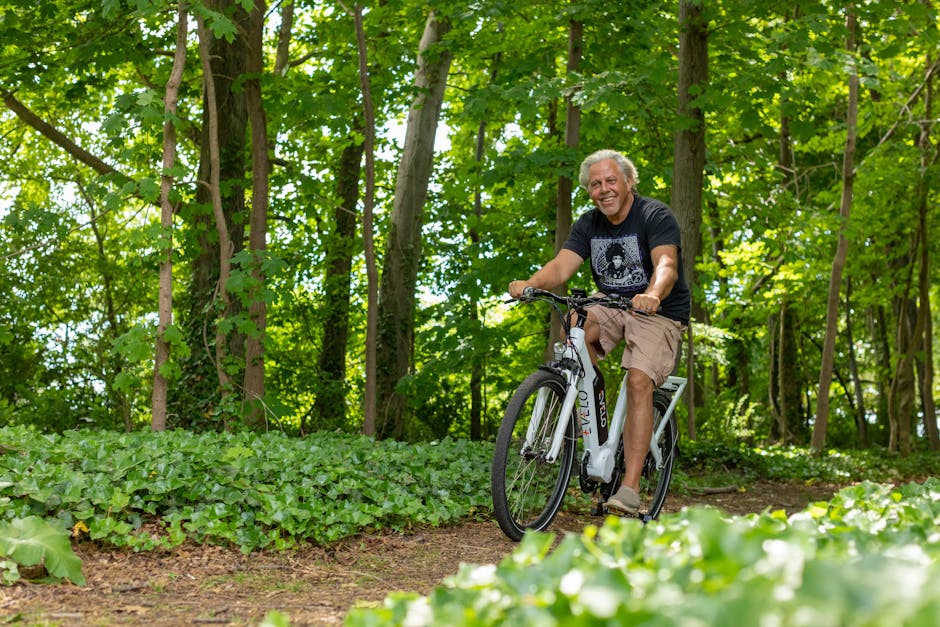 A man rides an electric bicycle through a lush green forest on a sunny day.