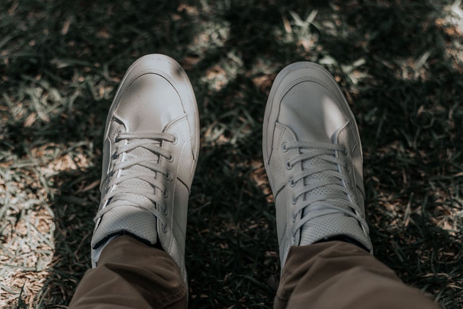 Pair of white sneakers on grass, showcasing casual outdoor style.