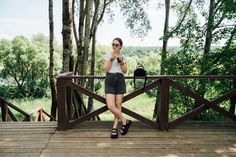 Woman in casual summer outfit enjoying coffee outdoors, surrounded by lush greenery.