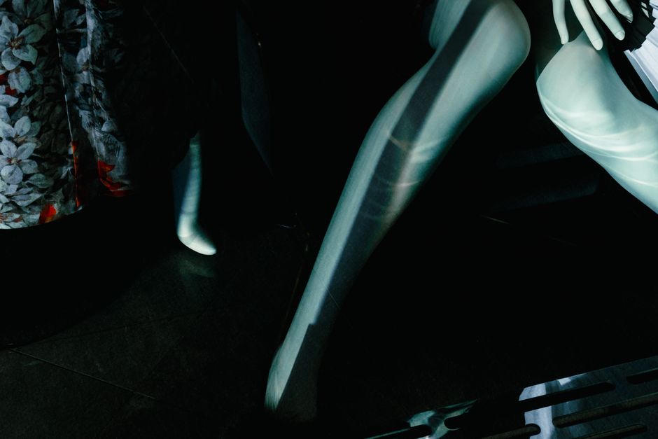 Artistic photograph of mannequin legs with dramatic shadows and floral patterns.