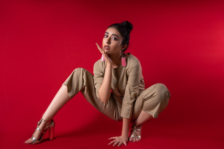 Modern fashion portrait of a woman posing against a bold red backdrop.