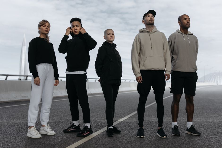 A diverse group of young adults in activewear standing confidently on a road, showcasing modern sports fashion.