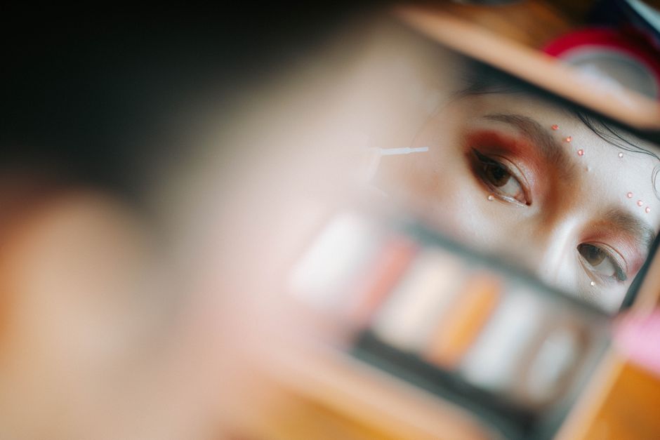 Close-up of artistic eye makeup reflected in a mirror, showing vivid colors and precise application.
