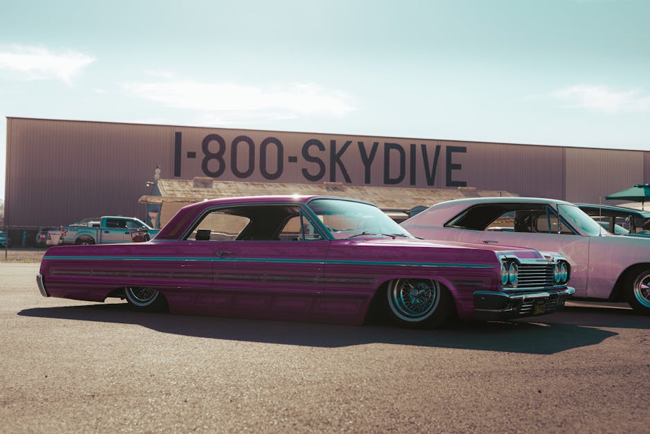 A vibrant display of vintage cars under a clear summer sky at a car show.