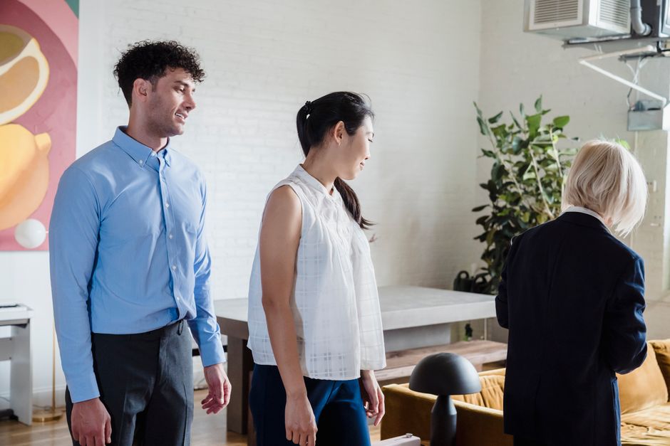 Multicultural professionals stand together in a modern office with artwork and plants.