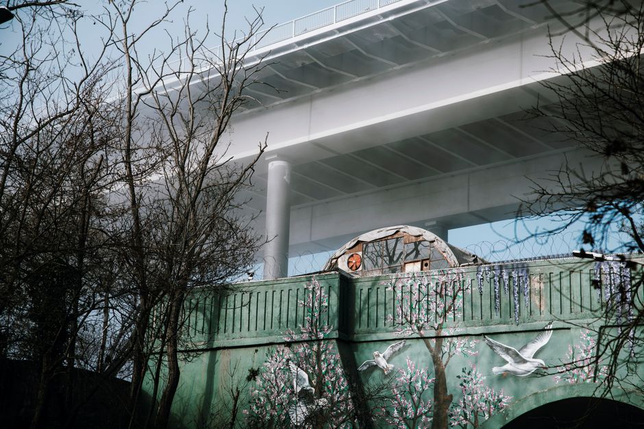 Elevated bridge with a vibrant mural featuring doves and trees, under clear skies.