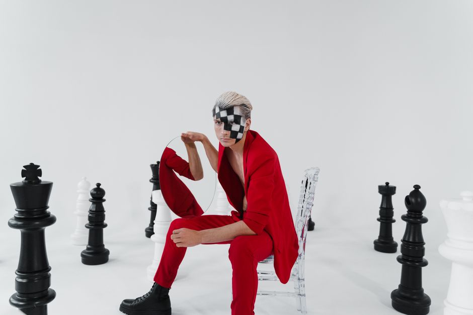 Creative fashion portrait with face paint amid oversized chess pieces.