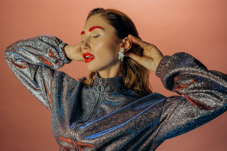 Stylish woman in a glittering outfit with bold makeup, exuding glamour and elegance.