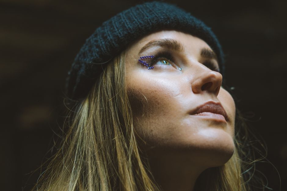 Close-up portrait of a woman with creative eye makeup, looking upward.