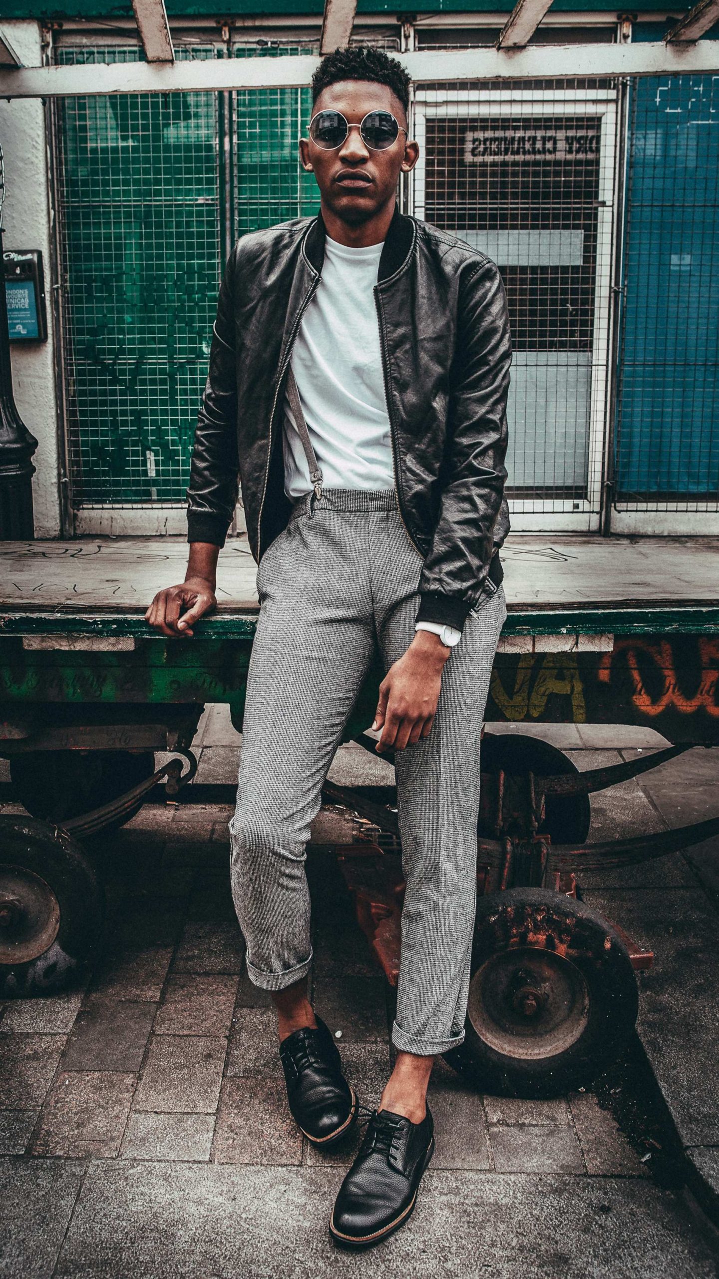 Man wearing sunglasses leather jacket and tailored trousers