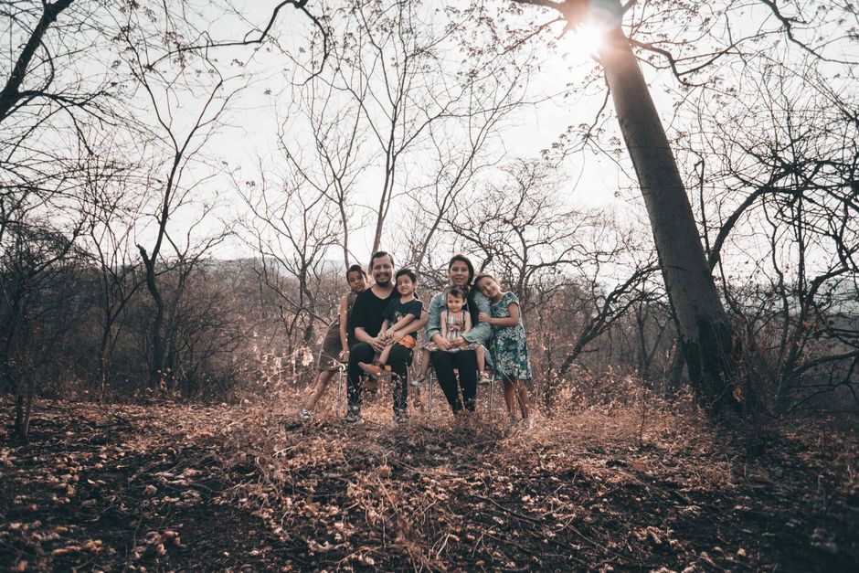 Family enjoying a sunny day sitting together in an autumn forest setting.