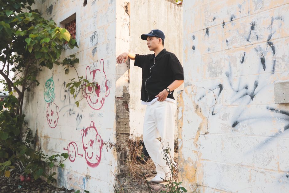 A man stands in an abandoned building with graffiti art, showcasing urban exploration.